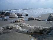 Winterimpressionen vom Ostseestrand: Eisreste und gefrorener Strandsand.