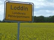 Nicht mehr a jour: Rapsfeld und alter Landkreisname am Ortschild des Seebades Loddin.