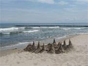 Usedomer Ostseestrand: Weier Sandstrand, Sandburg und blaues Meer.