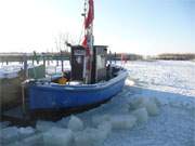 Eingefroren: Im Loddiner Achterwasserhafen wird ein Fischerboot vor dem wachsenden Eis geschtzt.