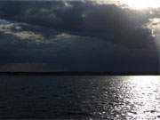 Dramaturgie der Natur: Das Achterwasser nahe der Insel Usedom unter Regenwolken.