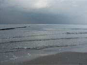 Verlassen liegt der Ostseestrand von Zempin unter einer dunklen Wolkendecke.