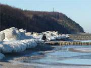 Hindernislauf: Strandspaziergnger neben und auf Eisbergen am Ostseestrand der Insel Usedom.