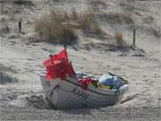 Mitten auf dem gerade geharkten Strand des Ostseebades Trassenheide liegt dieses Fischerboot.