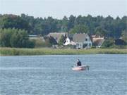 Angeln auf dem Peenestrom: Im Hintergrund Ferienhuser in Peenemnde auf Usedom.