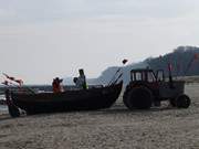 Ein alter Trecker zieht das Fischerboot auf den Ostseestrand.