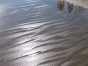 Spiegelungen im Strandsand: Spaziergnger am Strand.