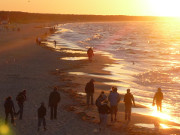 Urlaubsgäste bewundern den Sonnenuntergang am Meer.